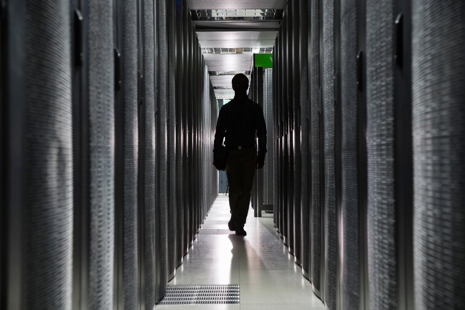 A technician walking between data center server racks
